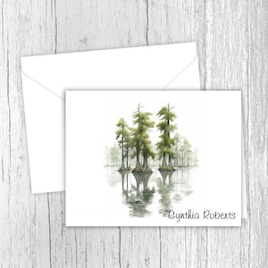 May include: A watercolor painting of a group of cypress trees reflected in a still body of water. The trees are green and brown, and the water is a light blue. The painting is signed "Cynthia Roberts" in the bottom right corner.