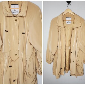 May include: A beige lightweight jacket with a drawstring waist and a zipper closure. The jacket has a label that says "Larry Levine" and a size "L".