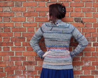 Handgemaakte gebreide gestreepte grijs gemêleerde wollen trui met lichtoranje patroon en knoopsluiting bij de hals