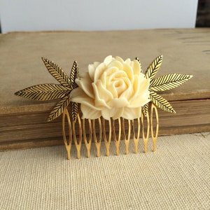 Peut inclure: Un peigne à cheveux doré avec une rose blanche et deux accents de feuilles dorées. Le peigne a un design décoratif et est parfait pour ajouter une touche d'élégance à n'importe quelle coiffure.