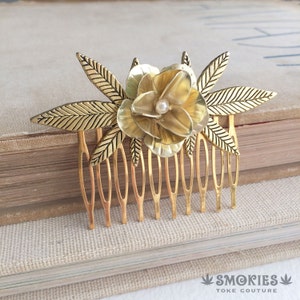 Peut inclure: Peigne à cheveux en or avec un motif de fleur et des feuilles. La fleur a une perle au centre.