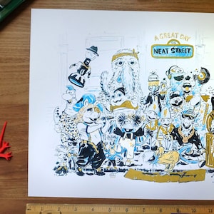 May include: A print featuring a colorful illustration of various cartoon characters, with the text "A Great Day on Neat Street." The artwork is in black, white, and gold, with a ruler at the bottom. The print is on a white background.