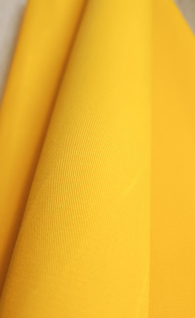 Close-up of yellow waxed cotton twill fabric with a textured surface.