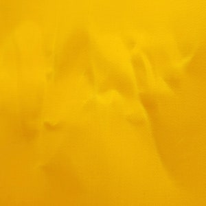 A close-up of a yellow waxed cotton twill fabric with a textured surface.