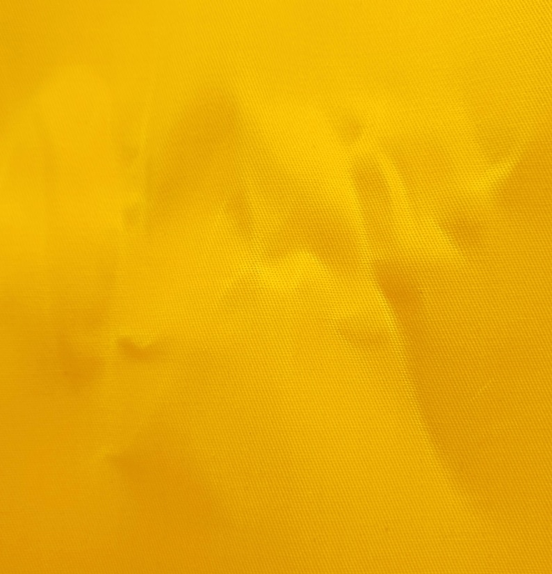 A close-up of a yellow waxed cotton twill fabric with a textured surface.