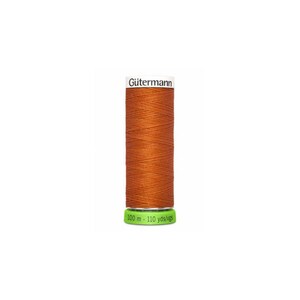 A spool of orange thread with a white label that reads 'Gütermann' and a green label that reads '100 m - 110 yds/vgs'. Made of recycled fibers.