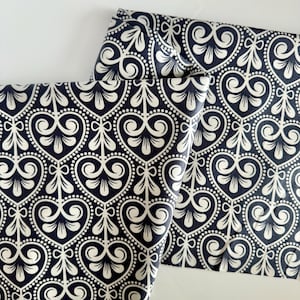 May include: Black and white fabric with a repeating pattern of stylized hearts and swirls. The fabric is folded in half, showing the pattern on both sides.