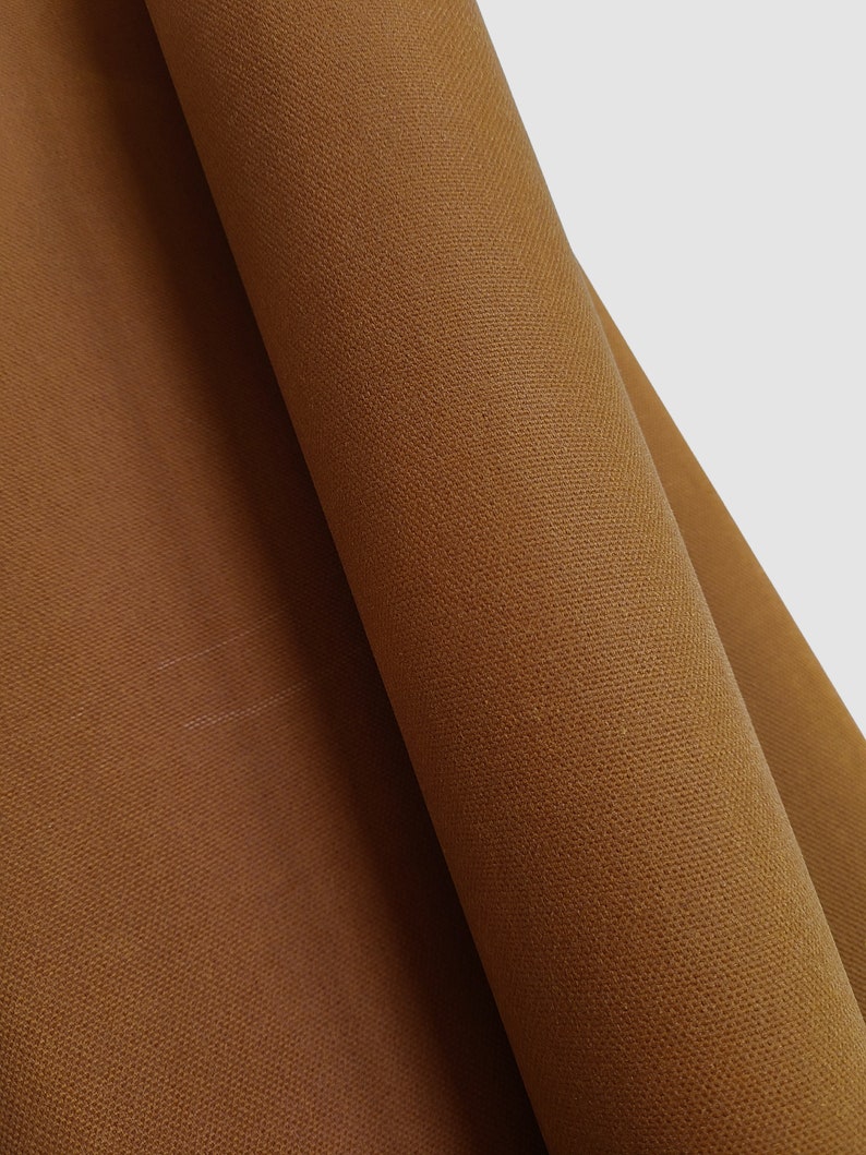 Close-up of a brown fabric with a textured surface. The fabric is folded over itself, creating a diagonal line.