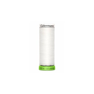 Puede incluir: Una bobina blanca de hilo Gutermann con una etiqueta verde que dice "100 m - 110 yds/mgs".