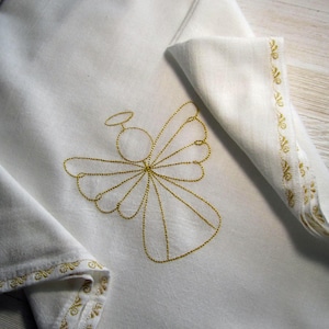 May include: White cloth with a gold embroidered angel design. The angel has a halo and wings. The cloth has a gold embroidered border.
