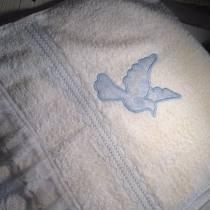May include: White bath towel with a blue embroidered dove design and a white lace trim.