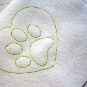 May include: A white fabric heart with a green embroidered paw print inside.