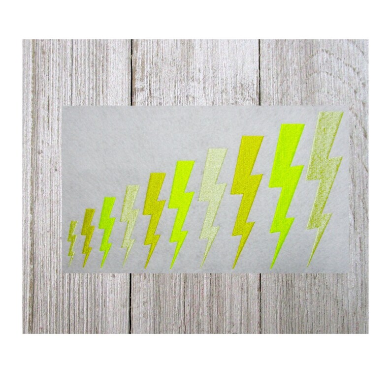 May include: A rectangular sticker featuring a series of yellow and light green lightning bolt designs. The bolts are arranged in a diagonal row, increasing in size from left to right. The sticker is on a light gray background.