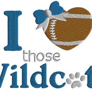May include: Embroidered design featuring the phrase "I love those Wildcats." The "I" is blue, the heart-shaped football is brown with white stripes and a blue bow. The word "Wildcats" is in blue, with a paw print.