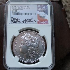 Puede incluir: Una moneda de plata de dólar Morgan de Carson City de 2021, clasificada MS70 por NGC. La moneda presenta un retrato de Lady Liberty y la inscripción "E Pluribus Unum".