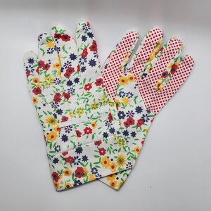 May include: A pair of gardening gloves with a floral print. One glove is white with red, yellow, and blue flowers, and the other is red with white polka dots.