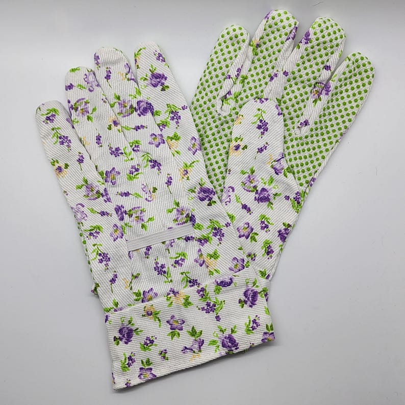 May include: A pair of gardening gloves with a floral print. One glove is white with purple flowers and the other is green with white polka dots.