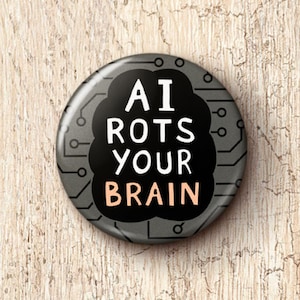 May include: A round button with the text "AI ROTS YOUR BRAIN" in white and peach lettering. The button has a gray background with a black cloud-like shape and a circuit board design around the edge.