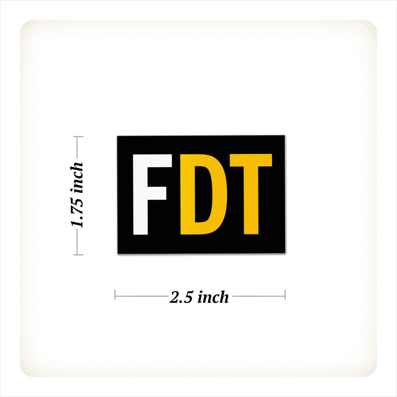 Może przedstawiać: Prostokątna naklejka z literami "FDT" w kolorze białym i złotym na czarnym tle. Naklejka ma 6,35 cm szerokości i 4,45 cm wysokości.