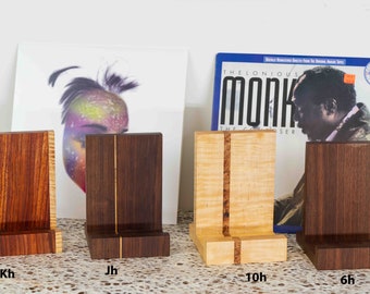 May include: Four wooden record stands with a single vertical groove down the center. The stands are made of different types of wood, including walnut, maple, and cherry. The stands are labeled Kh, Jh, 10h, and 6h.