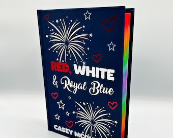 May include: A hardcover book with a navy blue cover featuring the title "RED, WHITE & Royal Blue" in white and red text. The cover design includes white fireworks, red hearts, and white stars. The author's name, Casey McQuiston, is printed at the bottom.