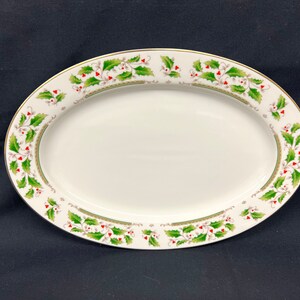 May include: White oval serving platter with a green and red holly leaf design around the edge.