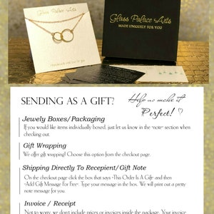 May include: A gold necklace with two interlocking circles, displayed on a white card with the text "Glass Palace Arts" and "Handmade with love for you". The card is sitting on a black box with the text "Glass Palace Arts" and "Made Uniquely For You".