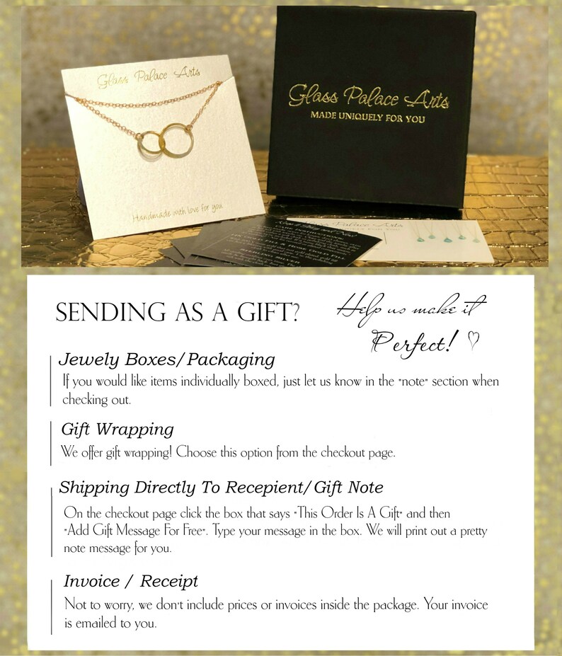 May include: A gold necklace with two interlocking circles, displayed on a white card with the text "Glass Palace Arts" and "Handmade with love for you". The card is sitting on a black box with the text "Glass Palace Arts" and "Made Uniquely For You".