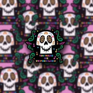 May include: A sticker featuring a colorful sugar skull with the text "You make me un poco loco" in a black and white font with a green, pink, and blue floral design.