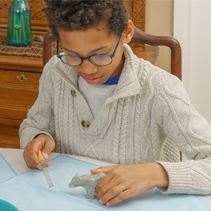 Boy carving soapstone bear with file