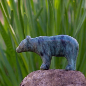 Soapstone bear sculpture on rock in nature