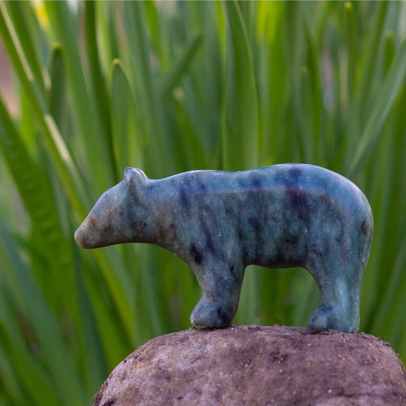 Soapstone bear sculpture on rock in nature