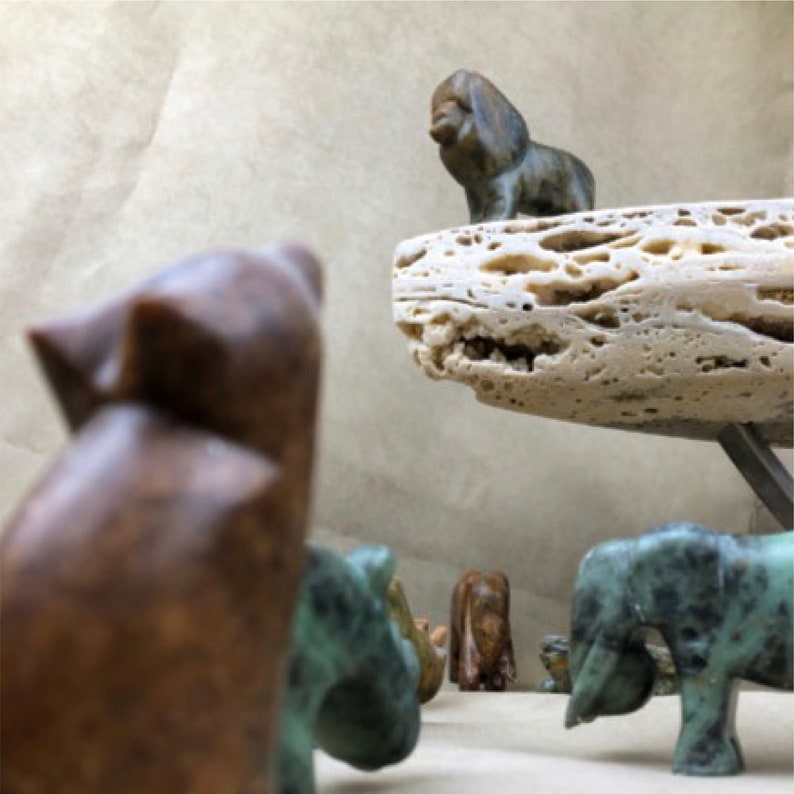 Soapstone lion sculpture on rock with elephant, wolf in foreground