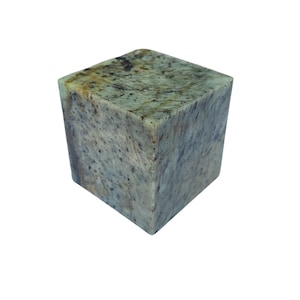 May include: A square, stone block with a mottled green and gray pattern. The cube-shaped object has rounded edges and a polished surface, showcasing natural variations in color and texture. The stone appears to be a decorative item.