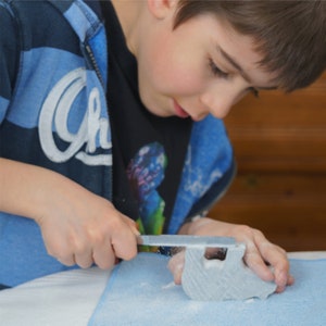 Boy carving soapstone bear with file