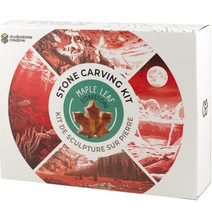 May include: A white box featuring a Stone Carving Kit. The kit includes a maple leaf soapstone. The box has a circular design with red and white illustrations of landscapes and the text "Stone Carving Kit" and "Kit de Sculpture sur Pierre".