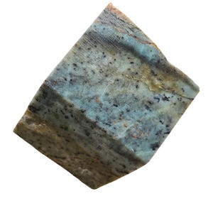 Pu&ograve; includere: Una pietra grezza di forma rettangolare con un mix di colori. La pietra presenta una base beige e marrone, con striature turchesi e macchie nere. I bordi sono irregolari, conferendole un aspetto naturale e grezzo.
