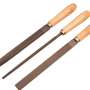 May include: Three metal rasps and files with light-colored wooden handles. The set includes one wide flat rasp, one narrow round file, and one wide flat file, each featuring a textured metal surface and a silver-colored metal ferrule.