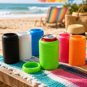 Puede incluir: Una colecci&oacute;n de enfriadores de latas cil&iacute;ndricos de espuma en negro, blanco, azul, verde lima, rosa y naranja. Un enfriador verde lima contiene una lata de aluminio plateada, con un anillo circular a juego sobre la superficie frontal.