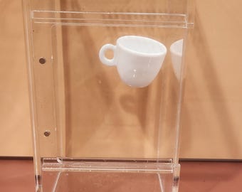 May include: A clear acrylic display case with a small white teacup inside. A stainless steel ruler is at the bottom of the image, showing inch measurements.