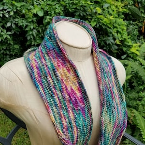May include: A colorful knitted infinity scarf with a variety of shades of green, blue, purple, and yellow.