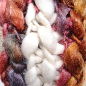 May include: A close-up of a colourful yarn blend with a mix of white, brown, red, and purple fibres. The yarn is soft and fluffy, and it would be perfect for knitting or crocheting.