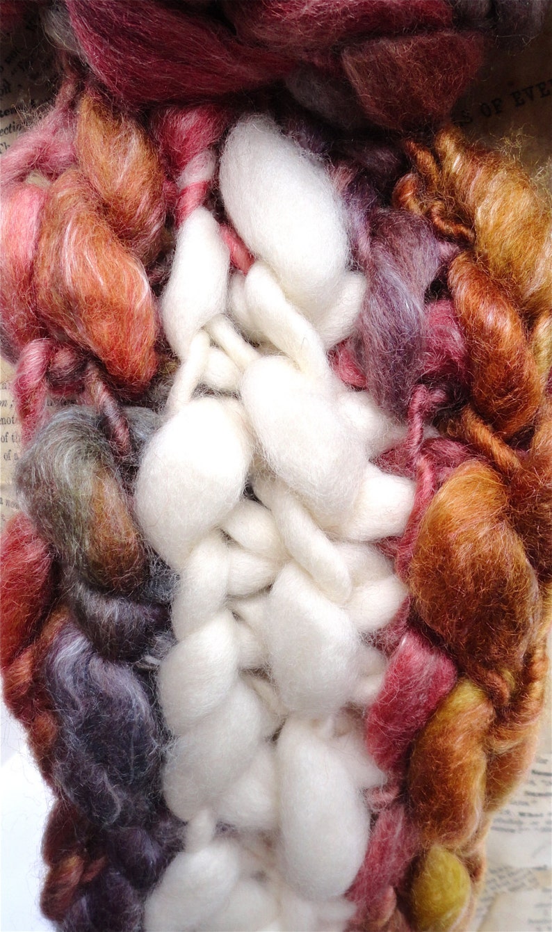 May include: A close-up of a colourful yarn blend with a mix of white, brown, red, and purple fibres. The yarn is soft and fluffy, and it would be perfect for knitting or crocheting.