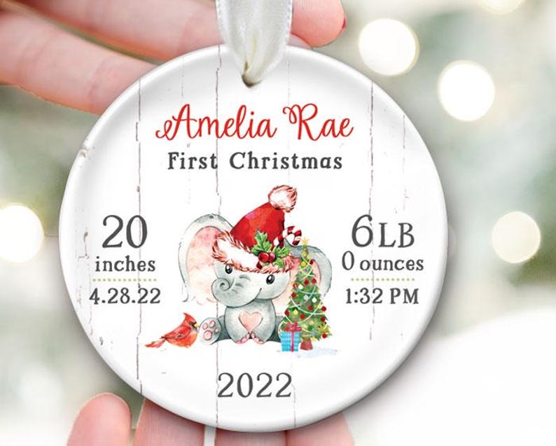 Pu&ograve; includere: Addobbo natalizio bianco con un adorabile elefante che indossa un cappello di Babbo Natale e tiene un albero di Natale. L'addobbo dice "Amelia Rae First Christmas" e include le statistiche di nascita del bambino: 20 pollici, 6 lb 0 oz, 4.28.22, 1:32 PM e 2022.