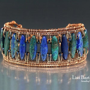 Op de afbeelding: Een armband omwikkeld met koperdraad met blauwe en groene ovale stenen. De armband is gemaakt met een geweven draadontwerp.