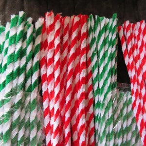 May include: Bundles of colorful pipe cleaners in green, red, and white. The pipe cleaners are twisted together, creating a striped pattern. These craft supplies are ideal for various DIY projects and holiday decorations.