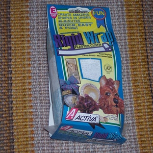 May include: A package of Rigid Wrap plaster cloth. The package is blue and white with the words "Rigid Wrap Plaster Cloth" in large letters. The package also features images of finished plaster projects and the text "Create Amazing Shapes in Under 30 Minutes".