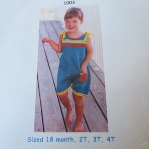May include: A child's blue knit romper with yellow and red accents. The romper has a pocket and yellow straps. The bottom hem is trimmed with yellow. Sizes available are 18 months, 2T, 3T, and 4T.