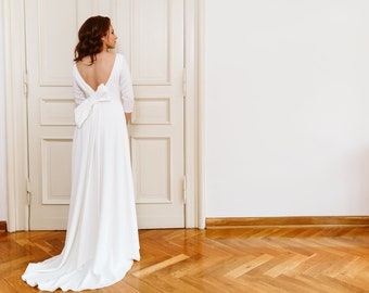 Minimalist wedding dress with an exposed back, bridal gown with train and bow, deep V-neck at the back