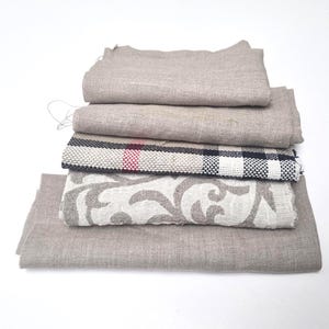 Puede incluir: Una pila de cinco muestras de tela diferentes en varios tonos de beige y marrón. La muestra superior es un lino beige liso, seguido de un lino beige con una textura sutil, luego una tela a cuadros en blanco y negro, una tela beige con un patrón floral y finalmente un lino beige liso.